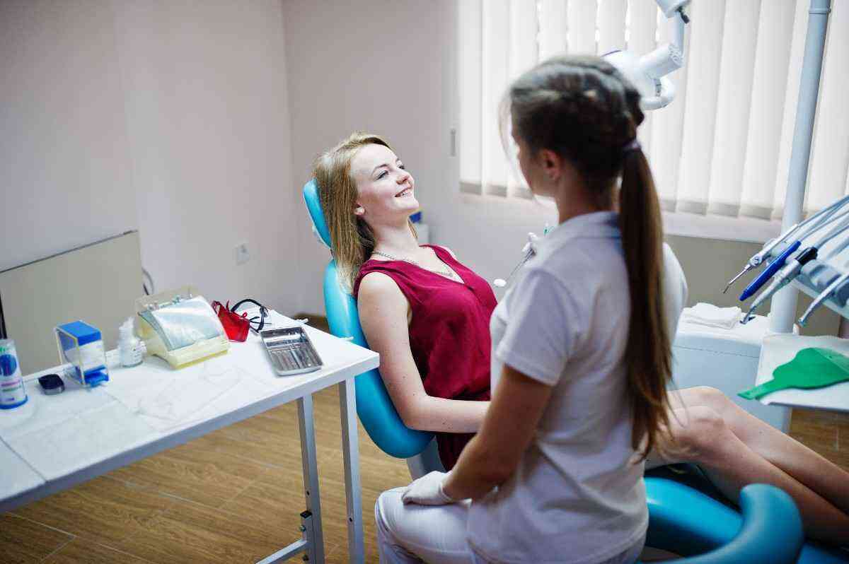 Patient smiling while consulting with a dentist during a routine dental checkup in a modern dental clinic