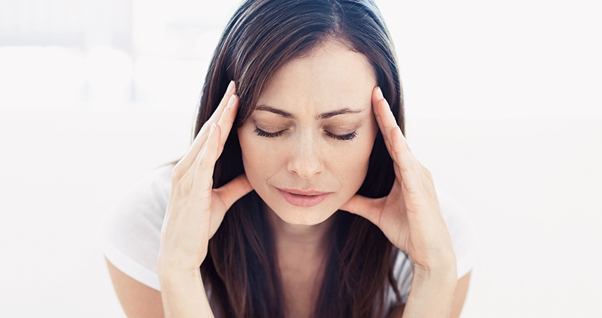 A woman holding her head visibly in pain from a headache
