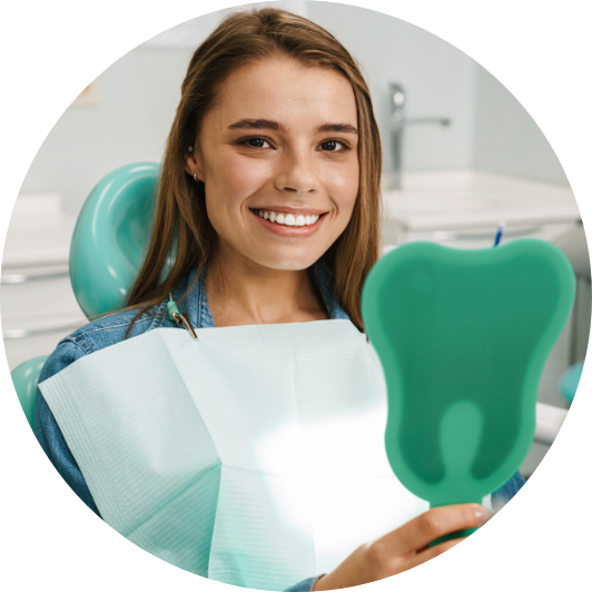 Smiling patient holding a tooth-shaped mirror after dental treatment.