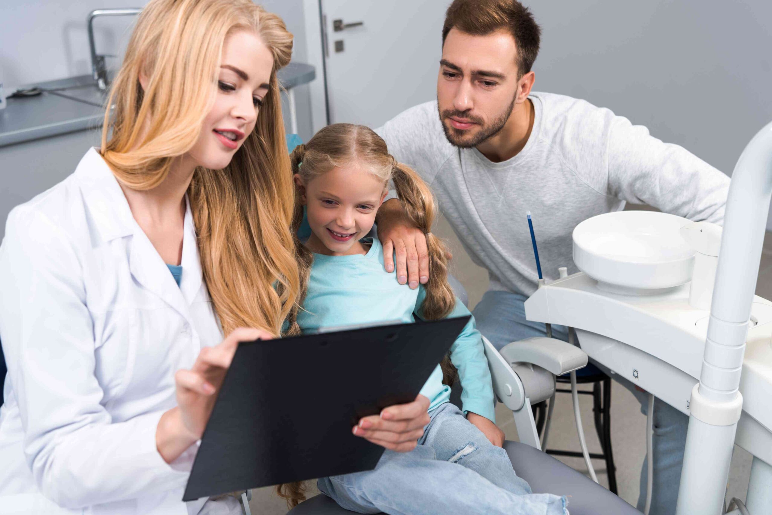 Dentist reviewing treatment information with a child and parent.