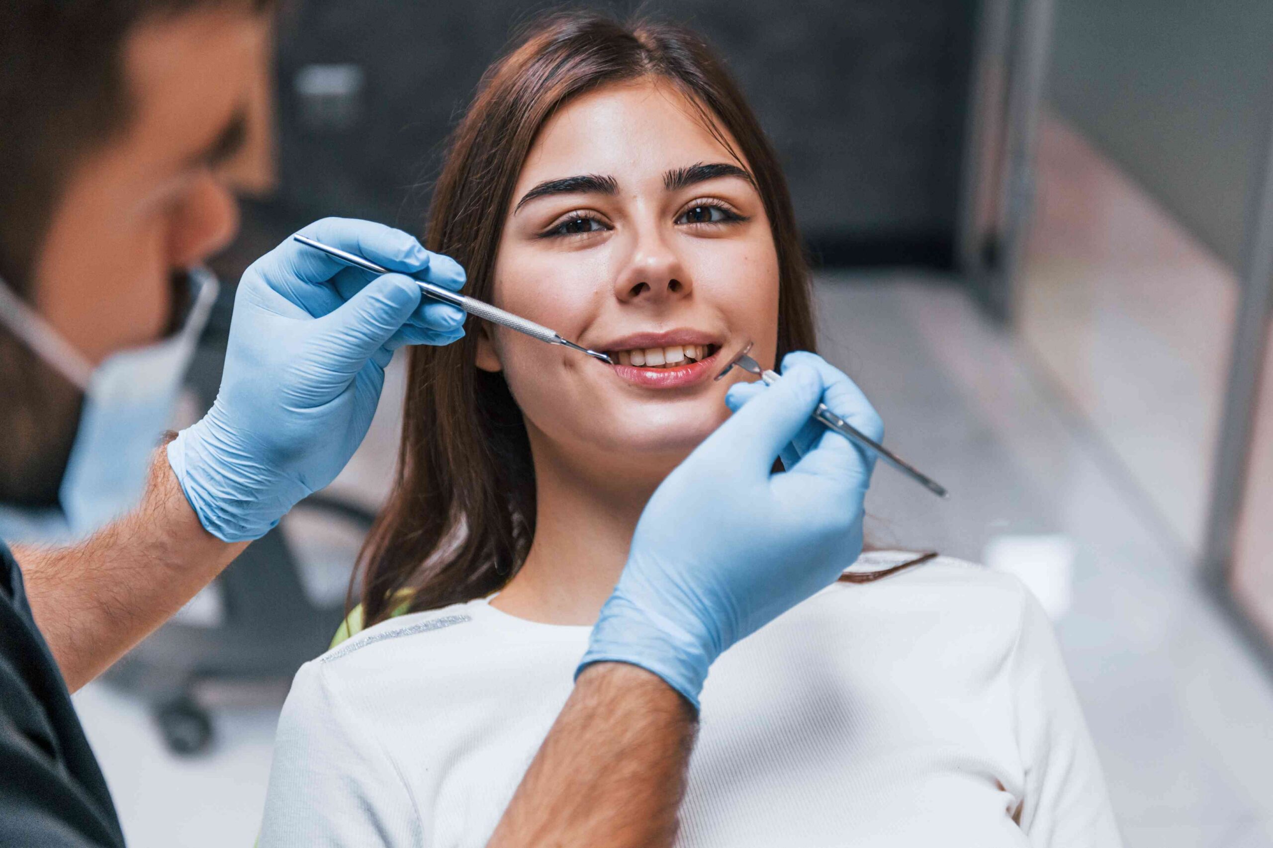 Dentist examining patient’s teeth with dental tools